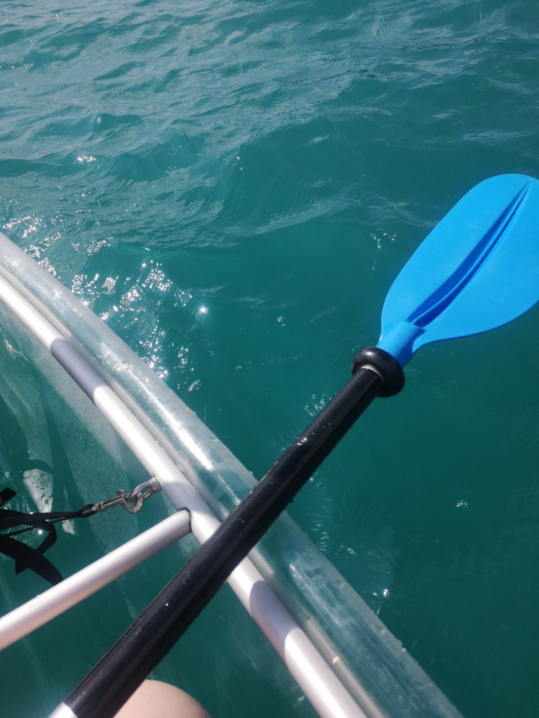The edge of my transparent kayak on bright blue water