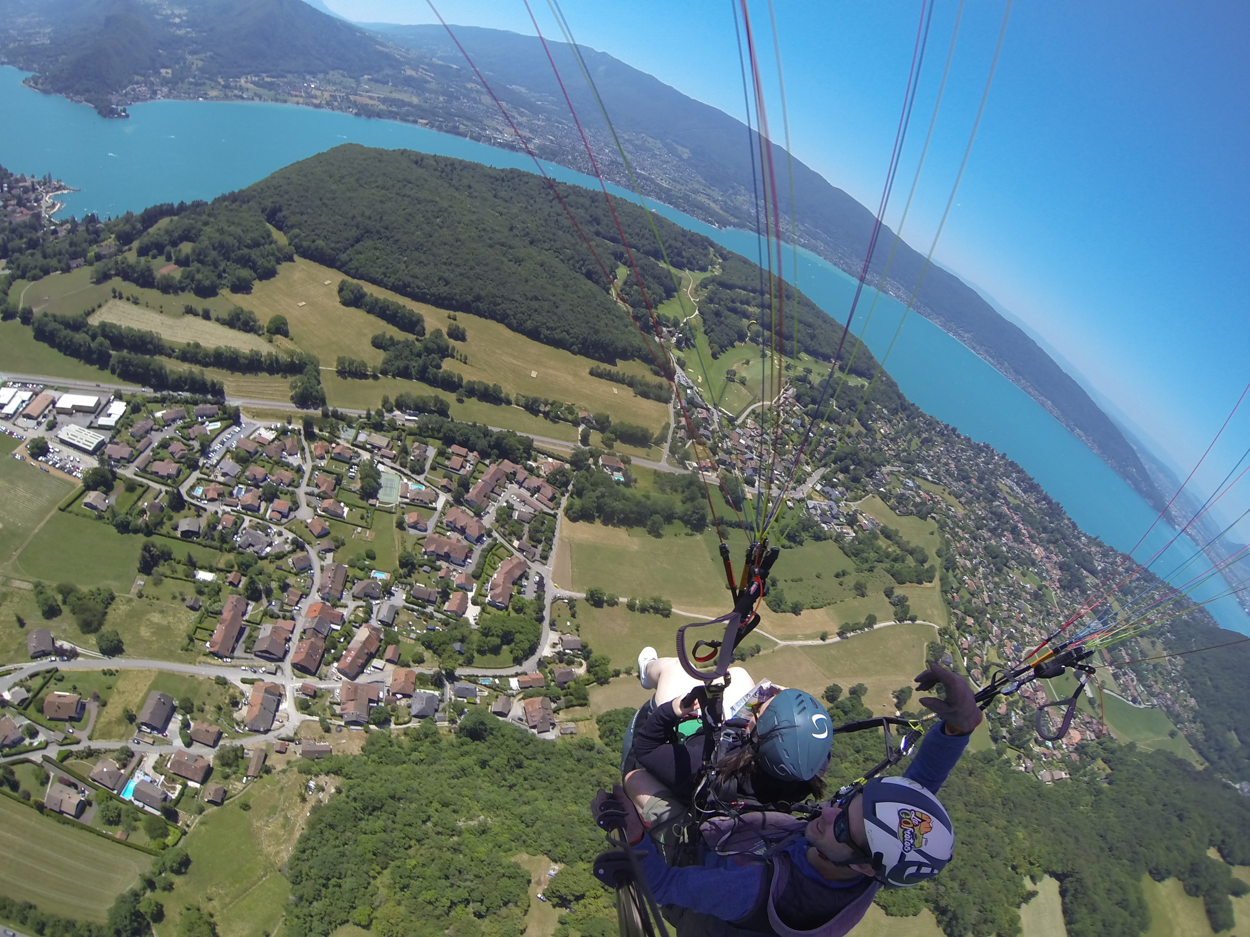 An overhead shot of me paragliding, strapped in to the pilot with the lake and fields underneath