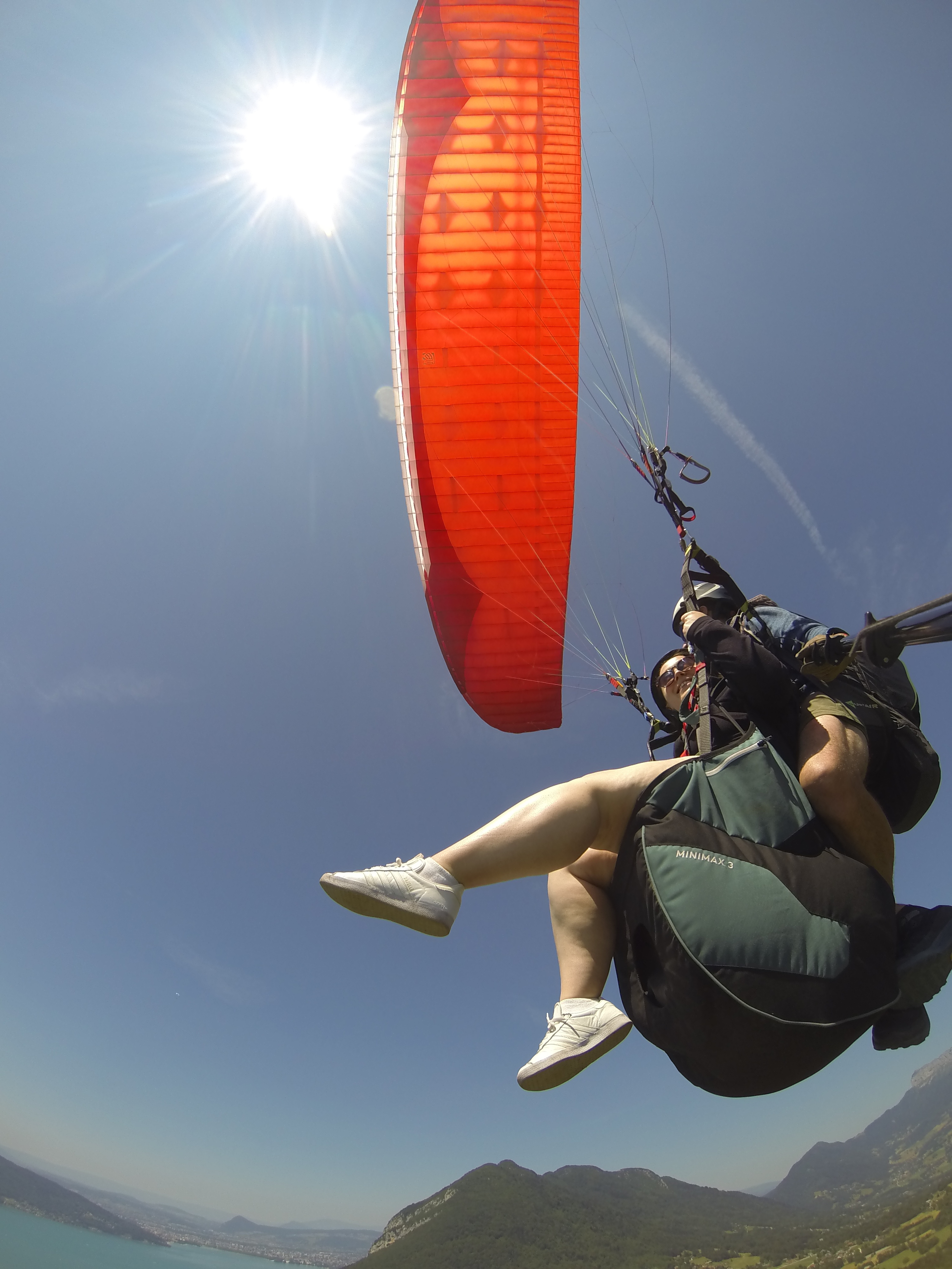 A shot from below looking up at me paragliding attached to the pilot and our parachute glinting in the sun