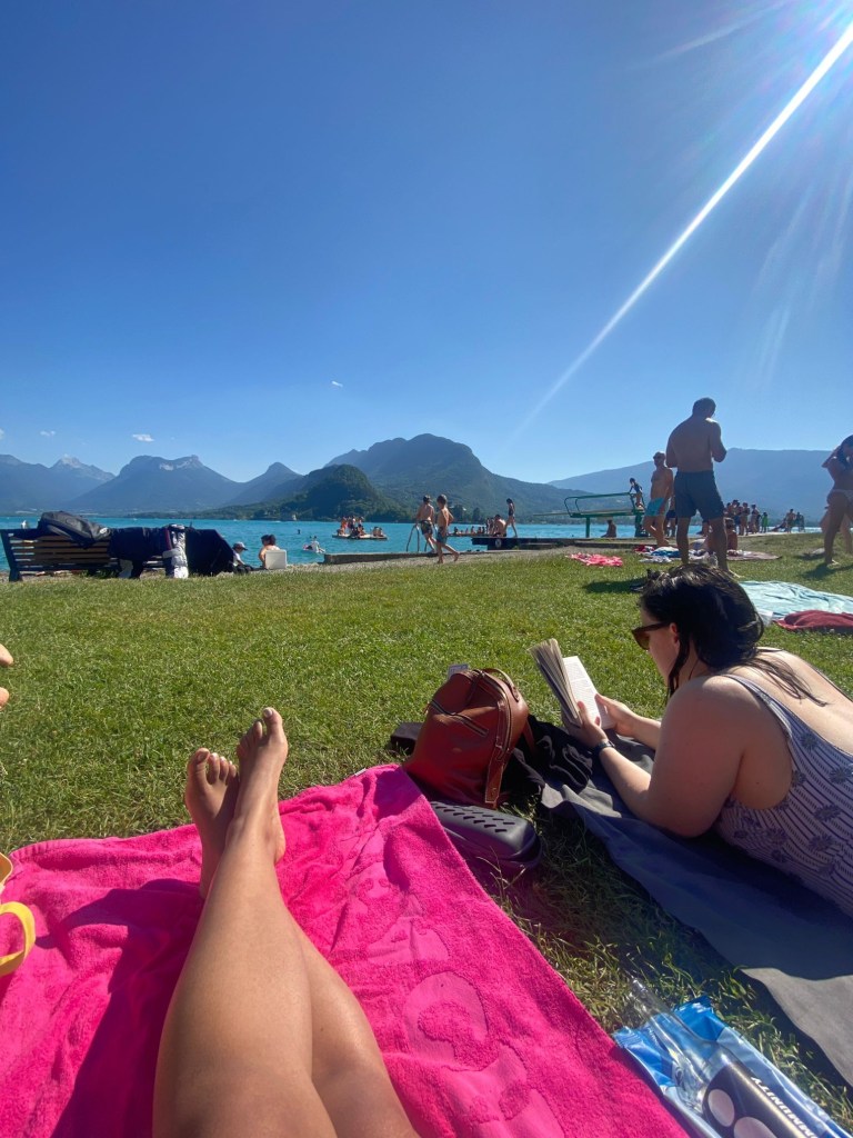 Danielle's legs stretched out on her towel while I read my book lying on my stomach