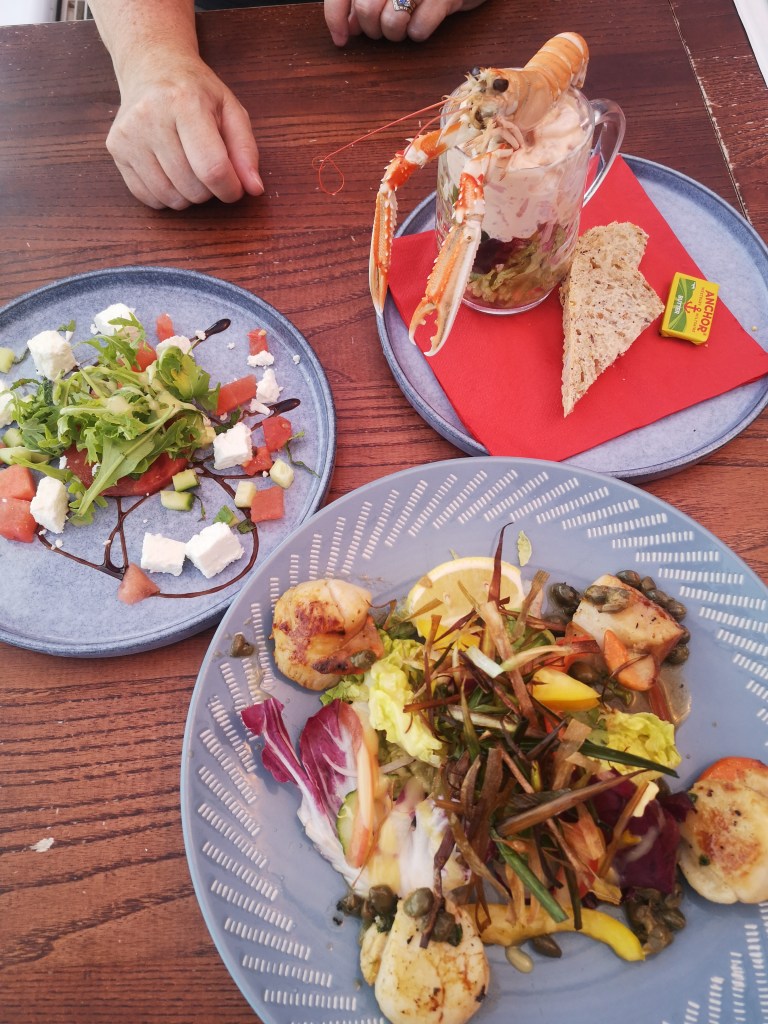 Dishes on a table with scallops, langoustines and salad