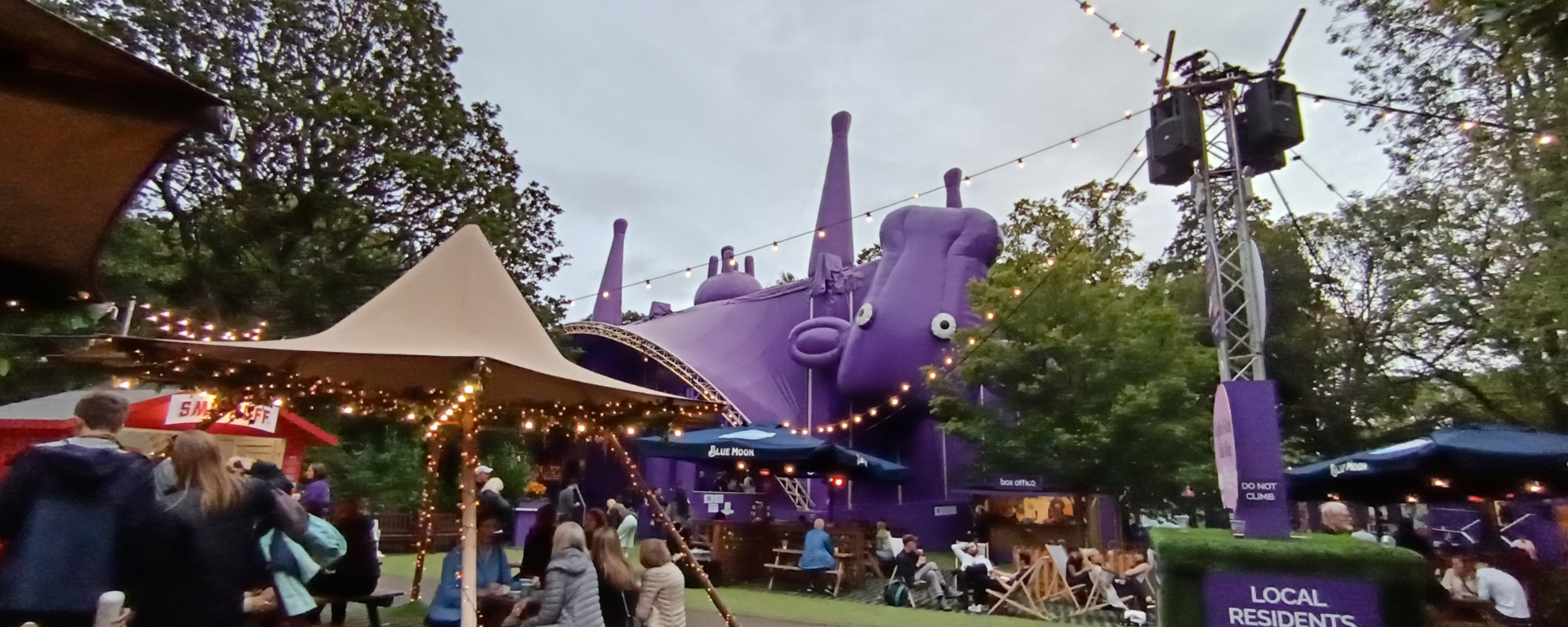 A festival garden strewn with lights and a giant upside down cow-shaped tent