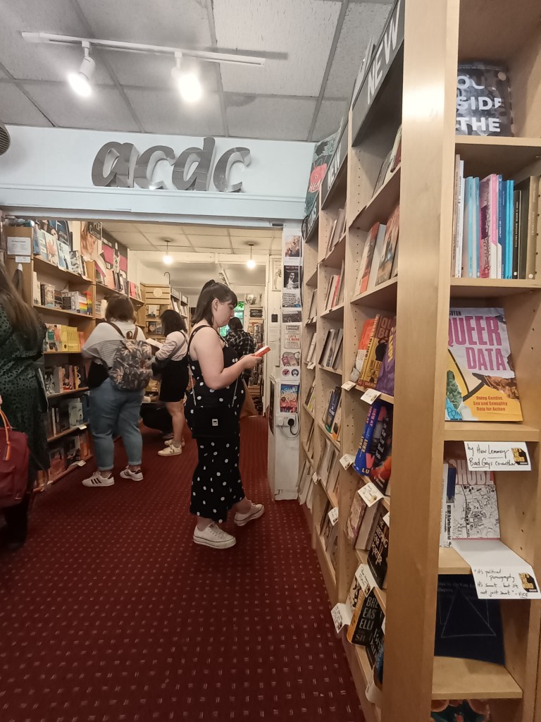 Erin holds a book as she stands in front of a tall bookshelf