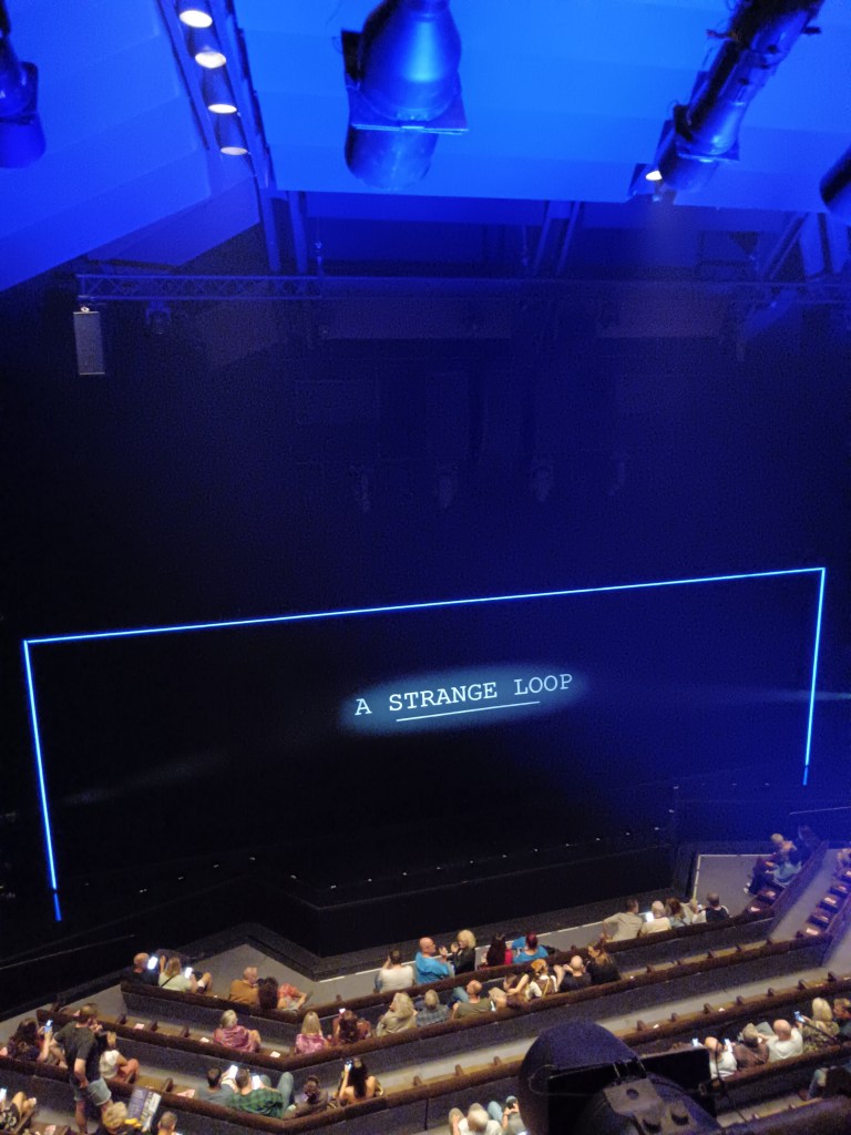 A black stage with the text A Strange Loop projected on it