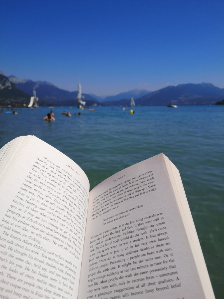 An open book held in front of a lake