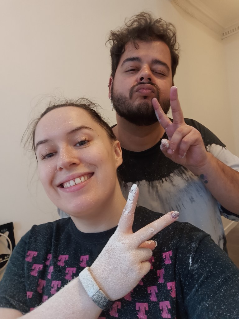 My friend and I pose with peace signs, covered in paint