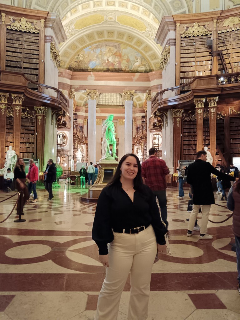 I stand smiling in front of a gorgeous library