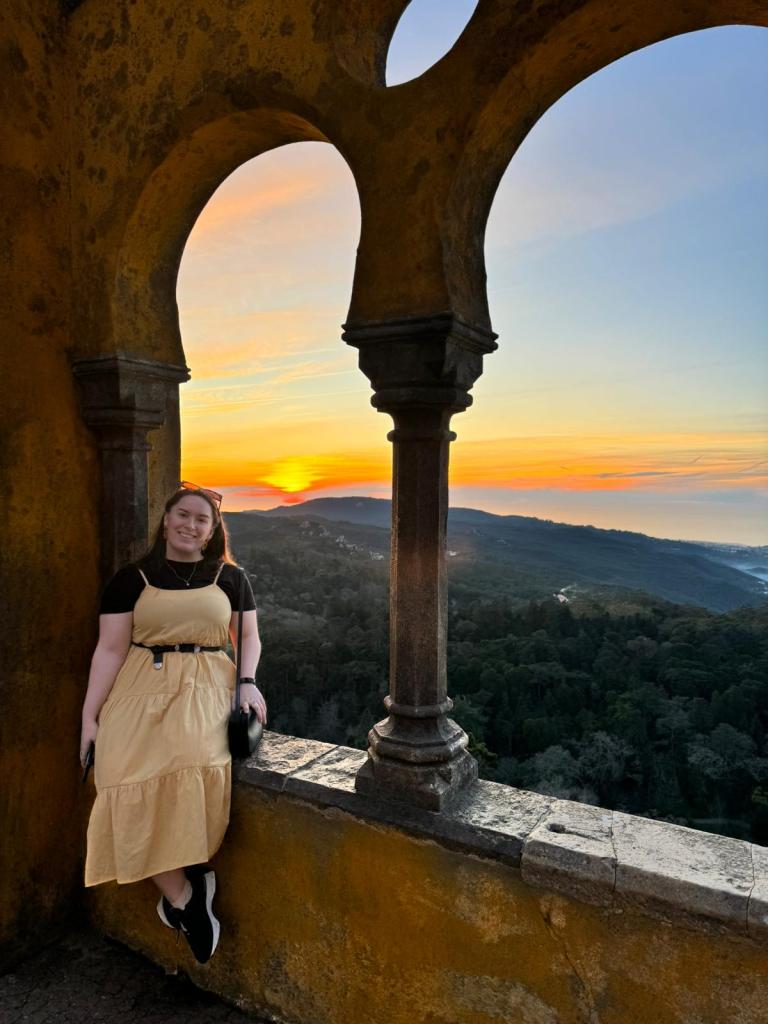 I sit on a ledge in front of a beautiful sunset