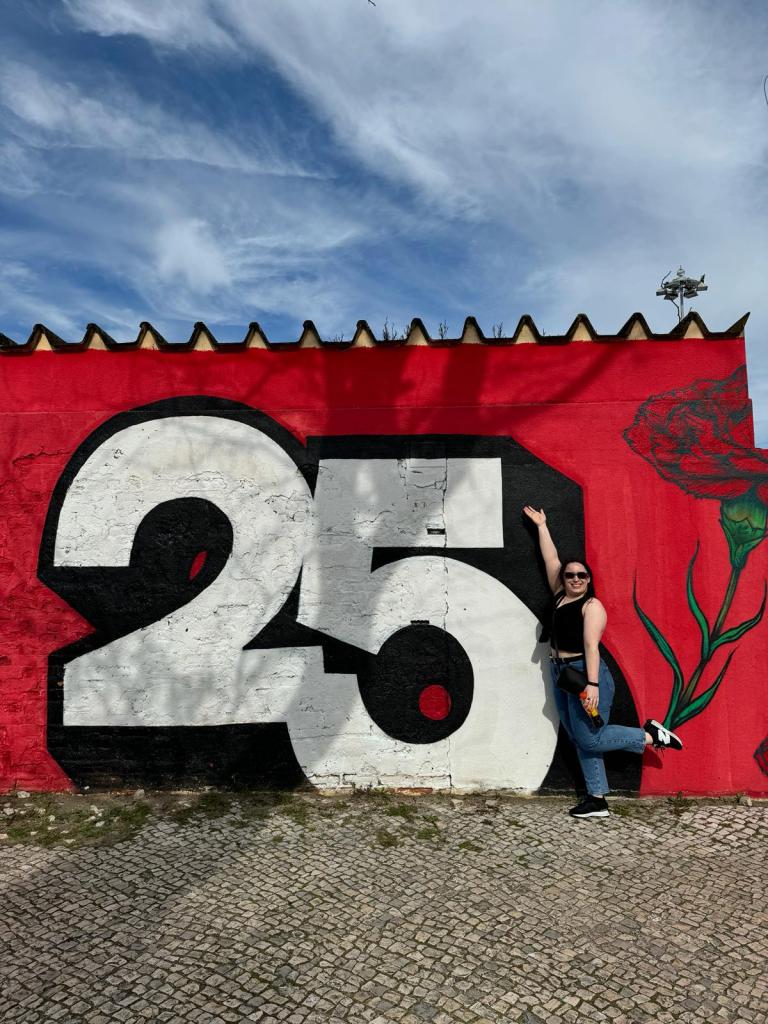 I pose in front of a wall that has a large 25 painted on it