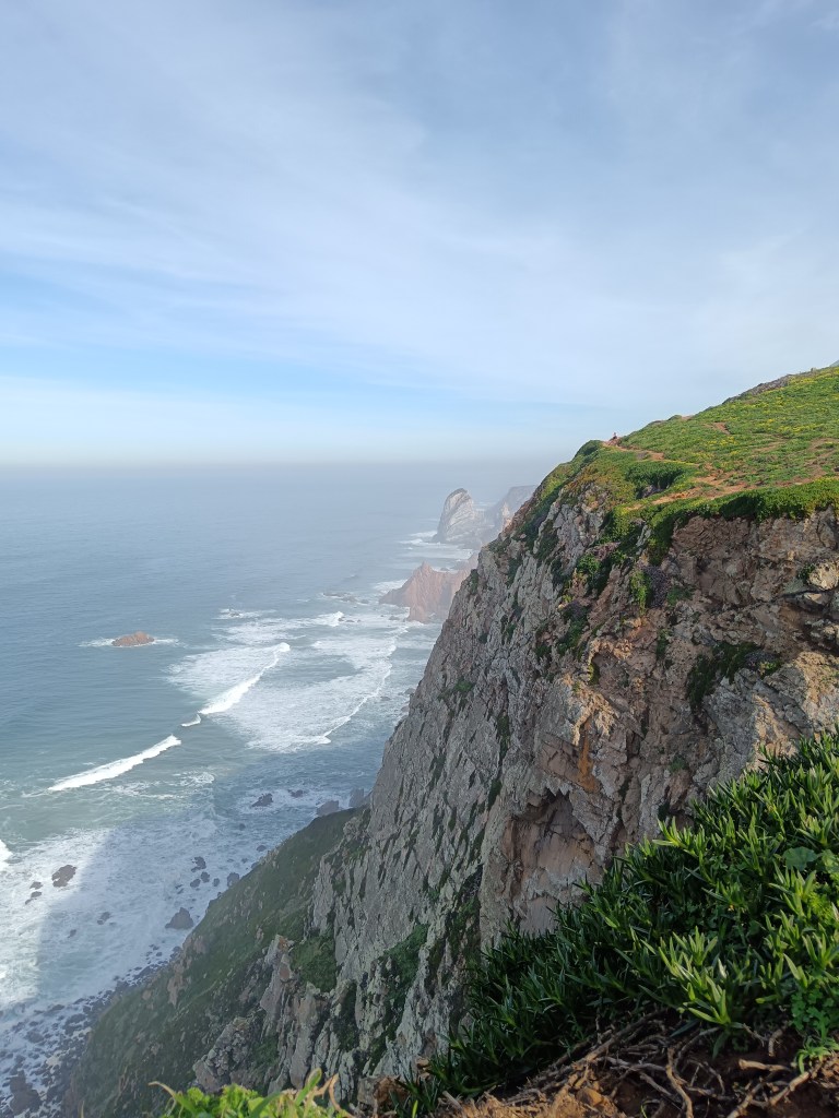 Waves come in along the cliff side