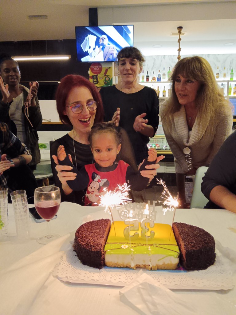 Deby smiles and holds her niece as the birthday candles burn