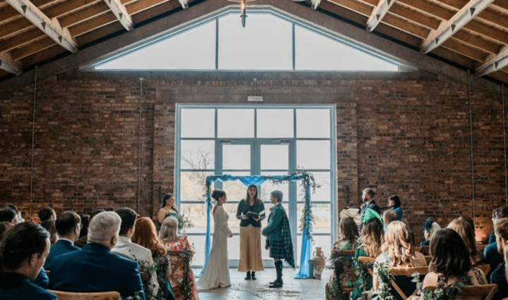 Two people stand at the top of an aisle between a celebrant