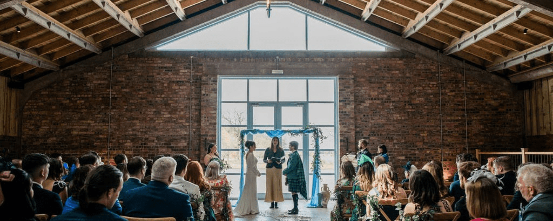 Two people stand at the top of an aisle between a celebrant