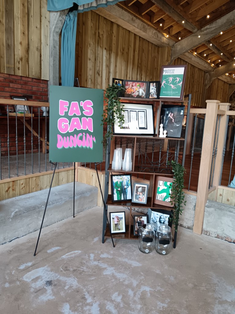 A shelf filled with pics of Claire and Grant throughout their lives and a big sign saying Fa's gan duncin'