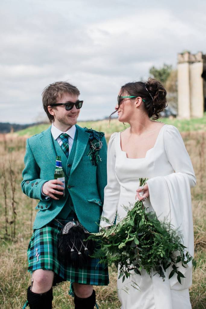 Bride and groom wearing sunglasses smile at each other