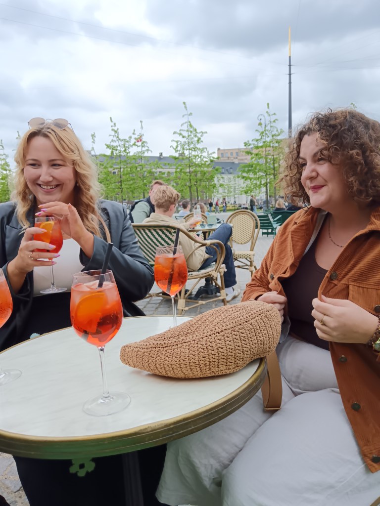 Hanna and Laura giggle while sipping spritz