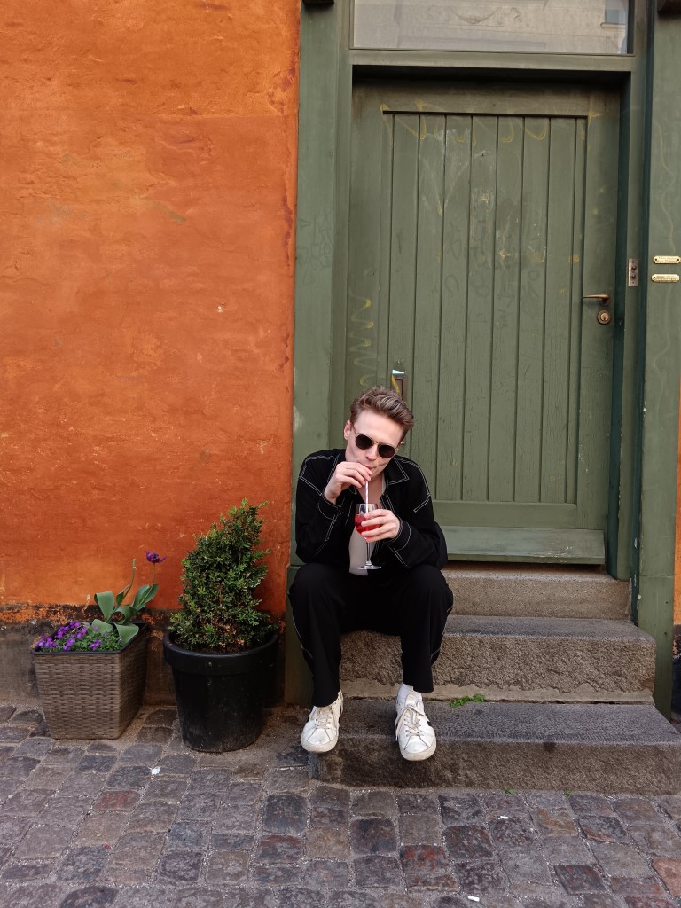 Jack sits on a doorstep sipping spritz