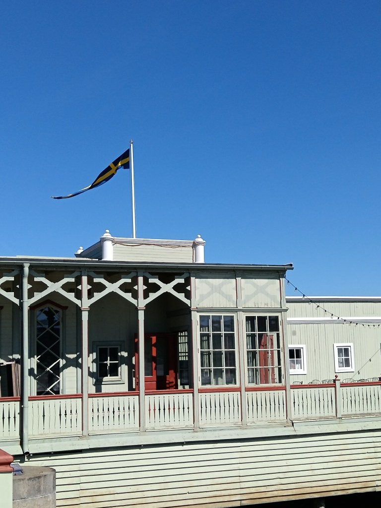 A pale green sauna house with Swedish flag