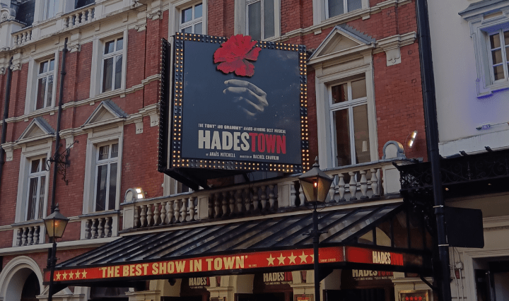 The exterior of a theatre in London with lights and signs that say Hadestown