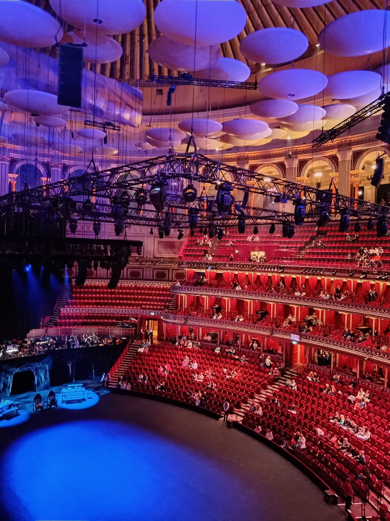 Royal Albert Hall red seats surround a stage with lights hanging over it