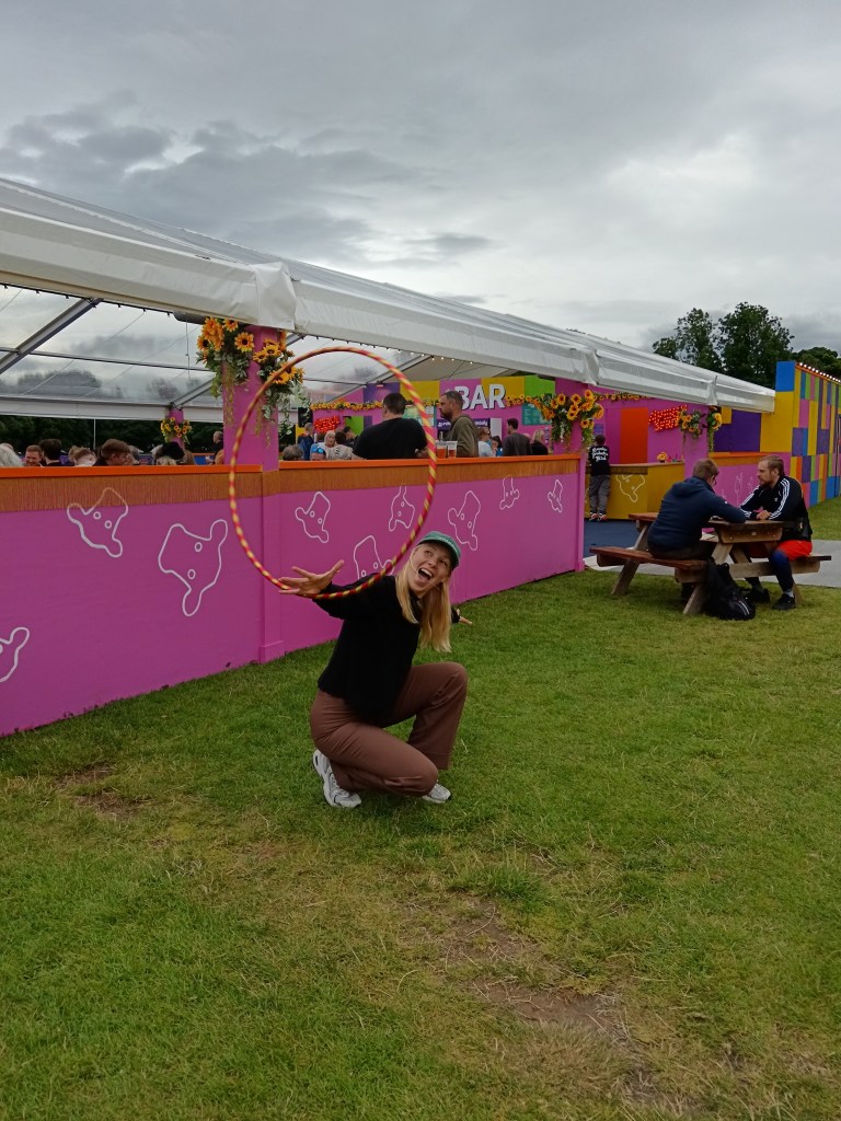 Matilda crouches while spinning a hoop on her hand