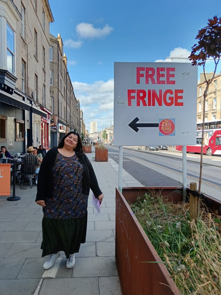 Sabina stands beside a Free Fringe sign