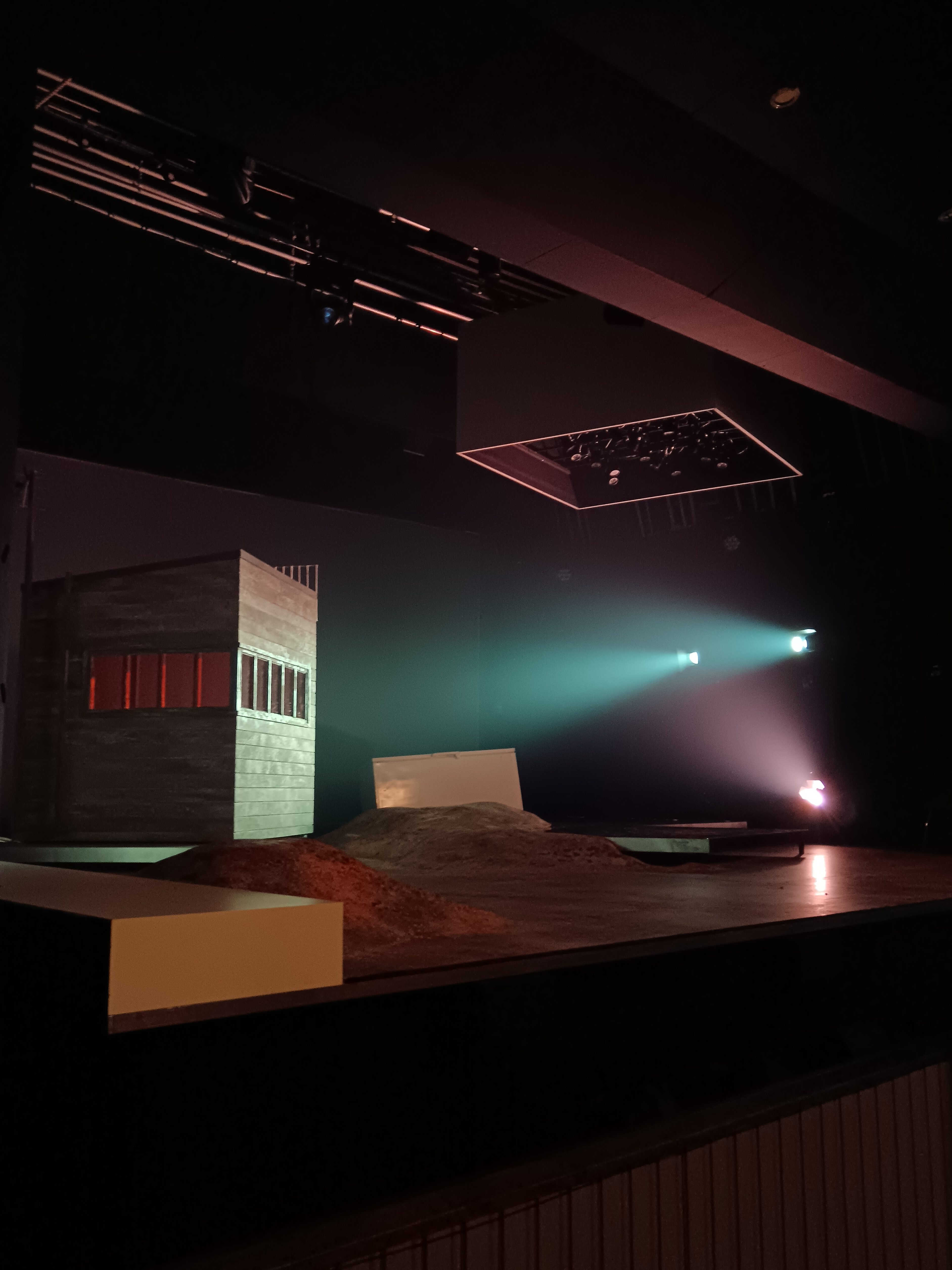 A simple stage with a wee house and lumpty rocks on the floor