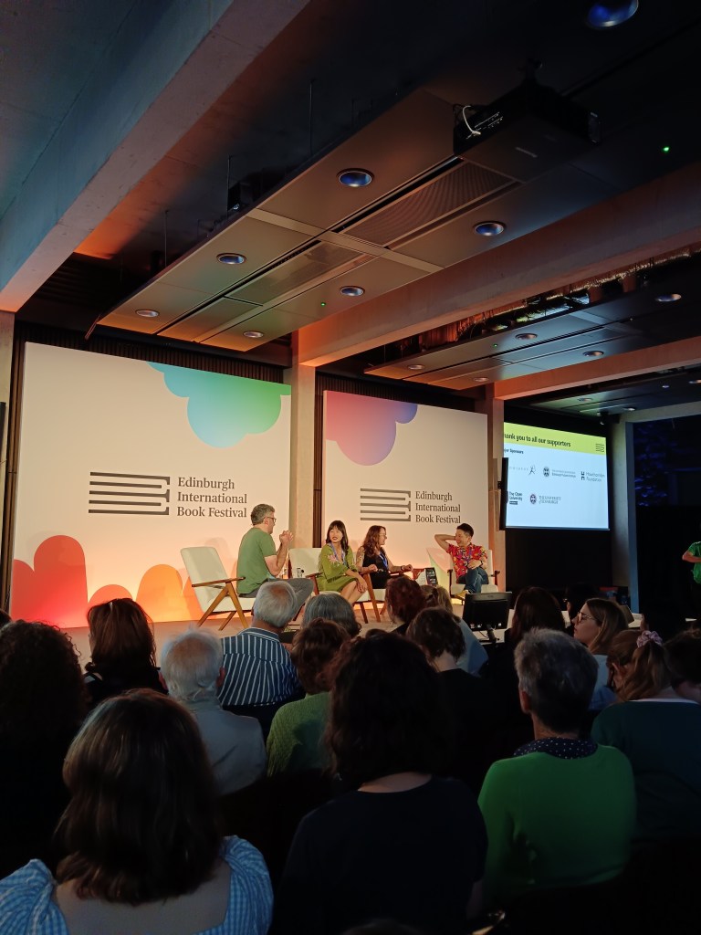 Authors sit on a panel on stage