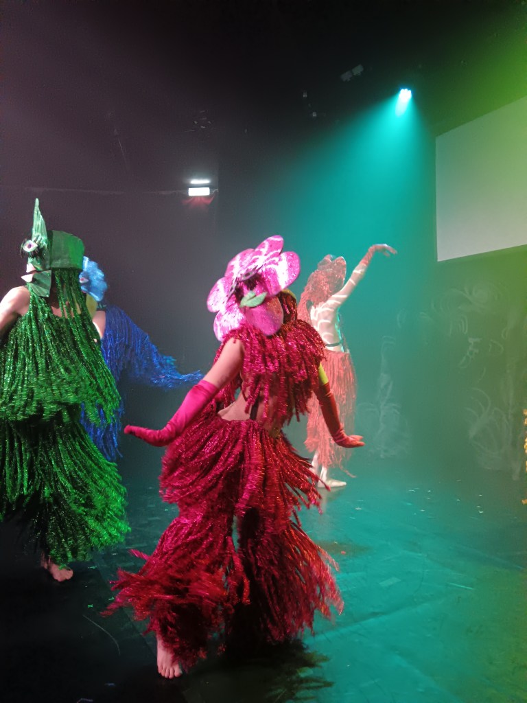 A fringed flower person dances