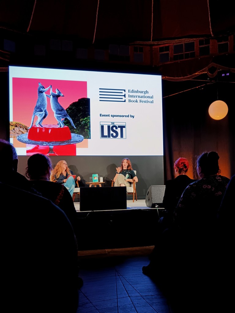 Fern and her interviewer sit on a stage