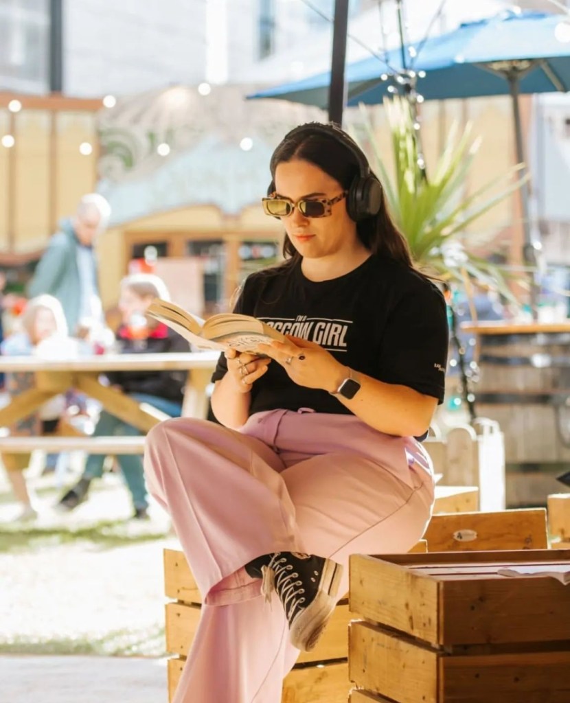I am reading a book with headphones and sunglasses on 