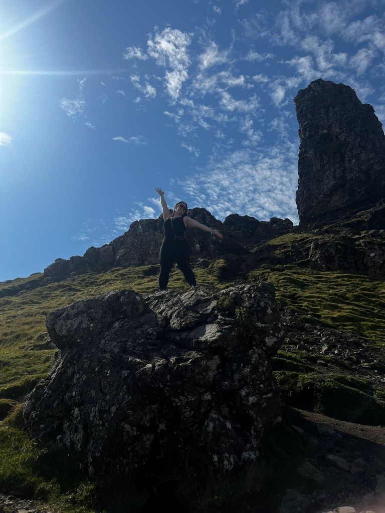 I hold my arms up standing on top of a rock
