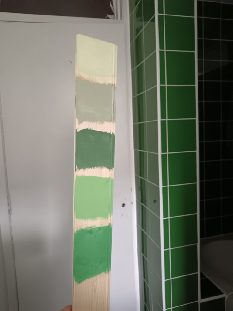 A piece of wood with different green paint samples