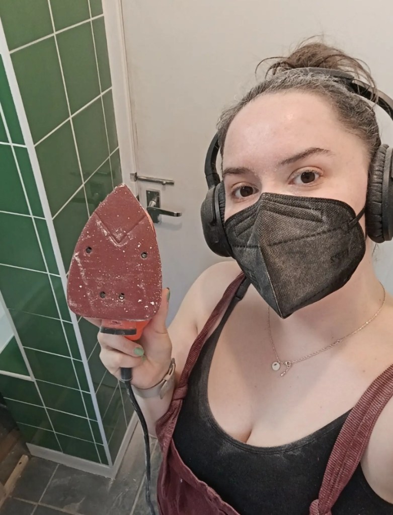 I smile behind a mask holding my sander