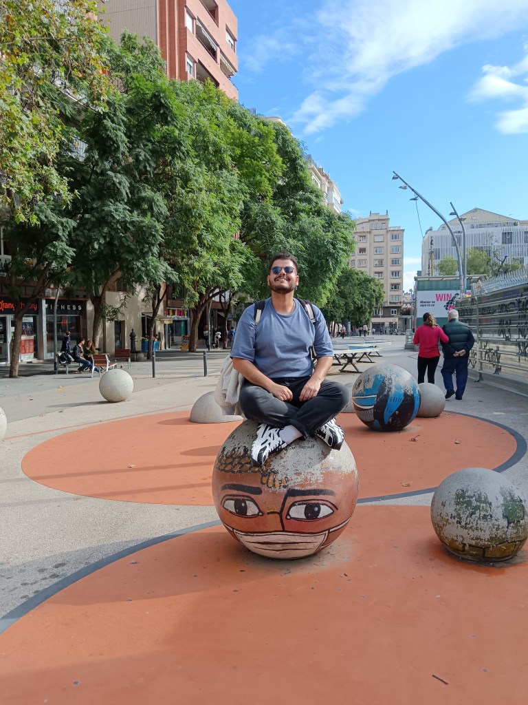 Bruno sits on a painted cement ball smiling