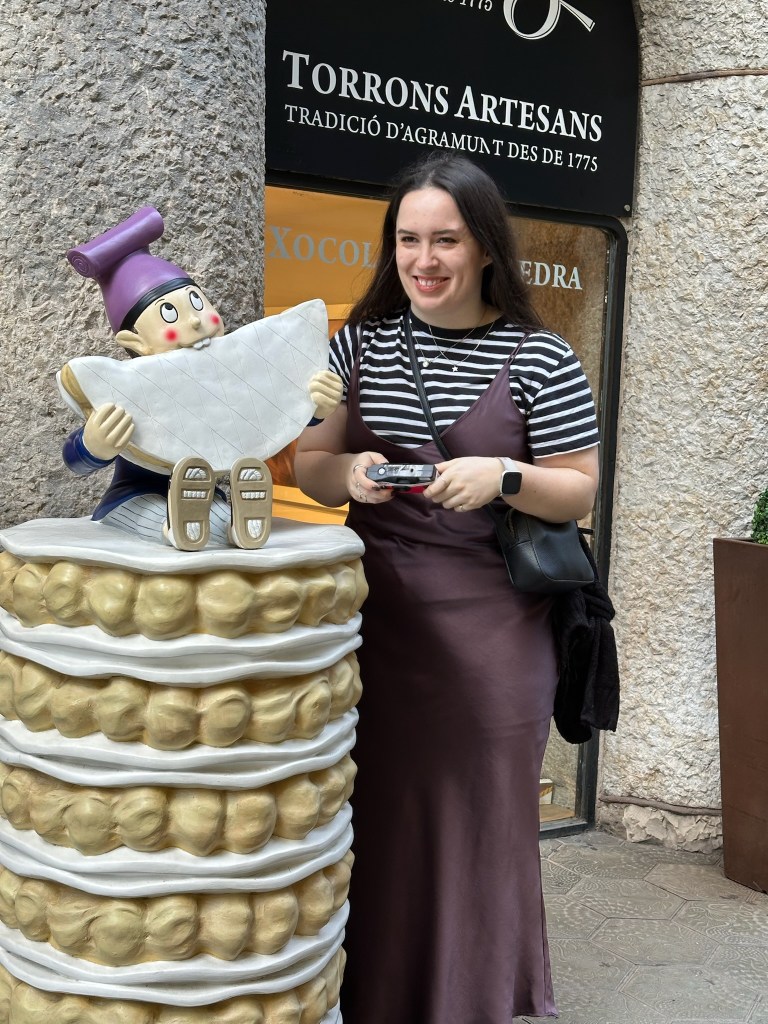 I smile next to a statue of an elf eating a cake