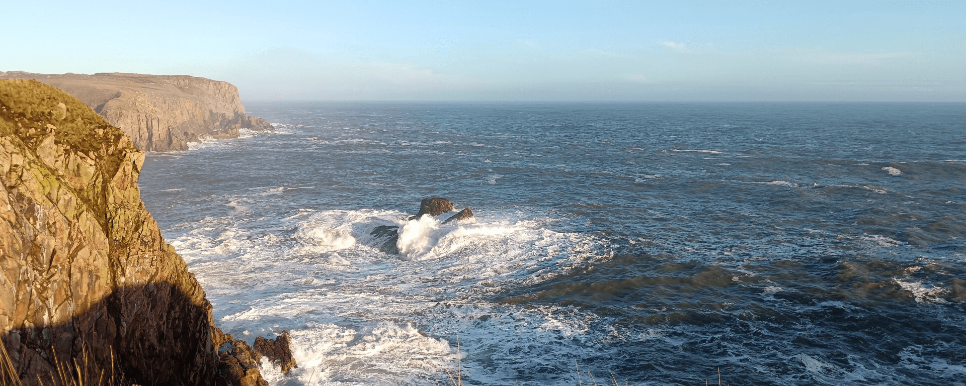 Waves crash around rocks under the cliffs