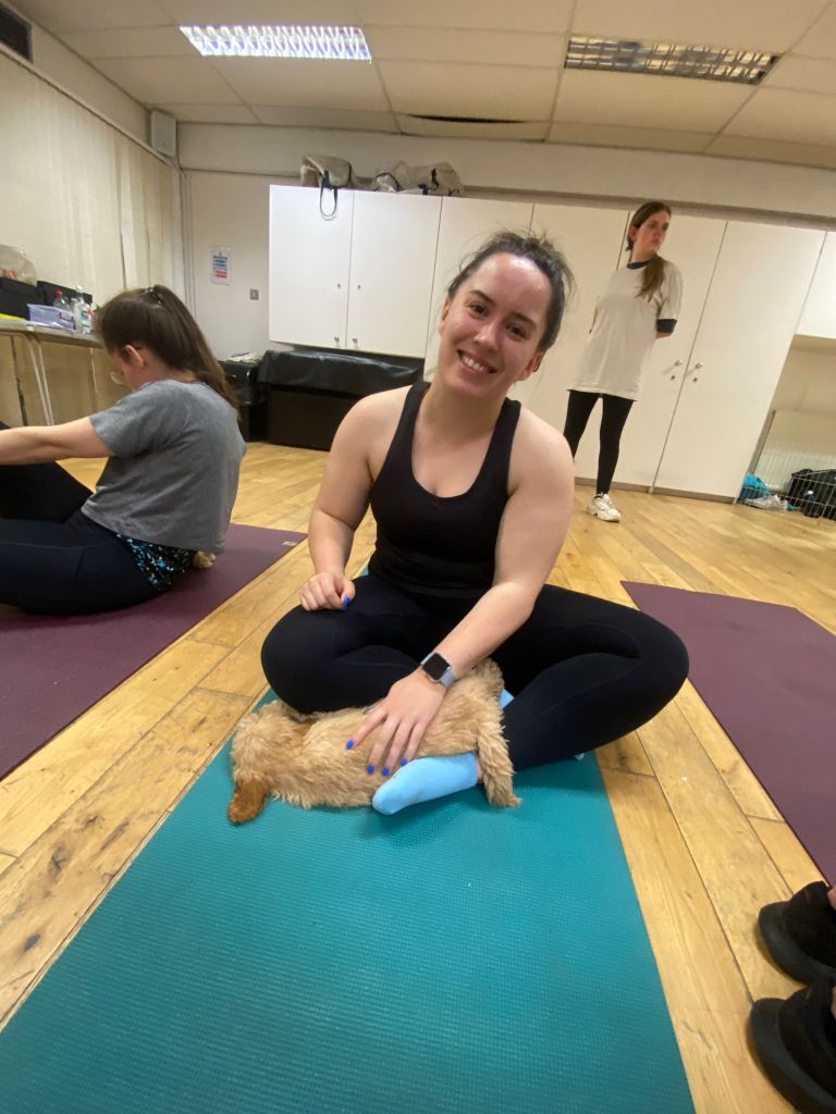 I smile with a sleeping puppy on a yoga mat