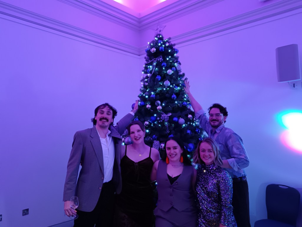Work pals smiling with xmas tree