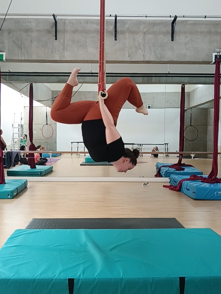 I hang under a trapeze with bent legs