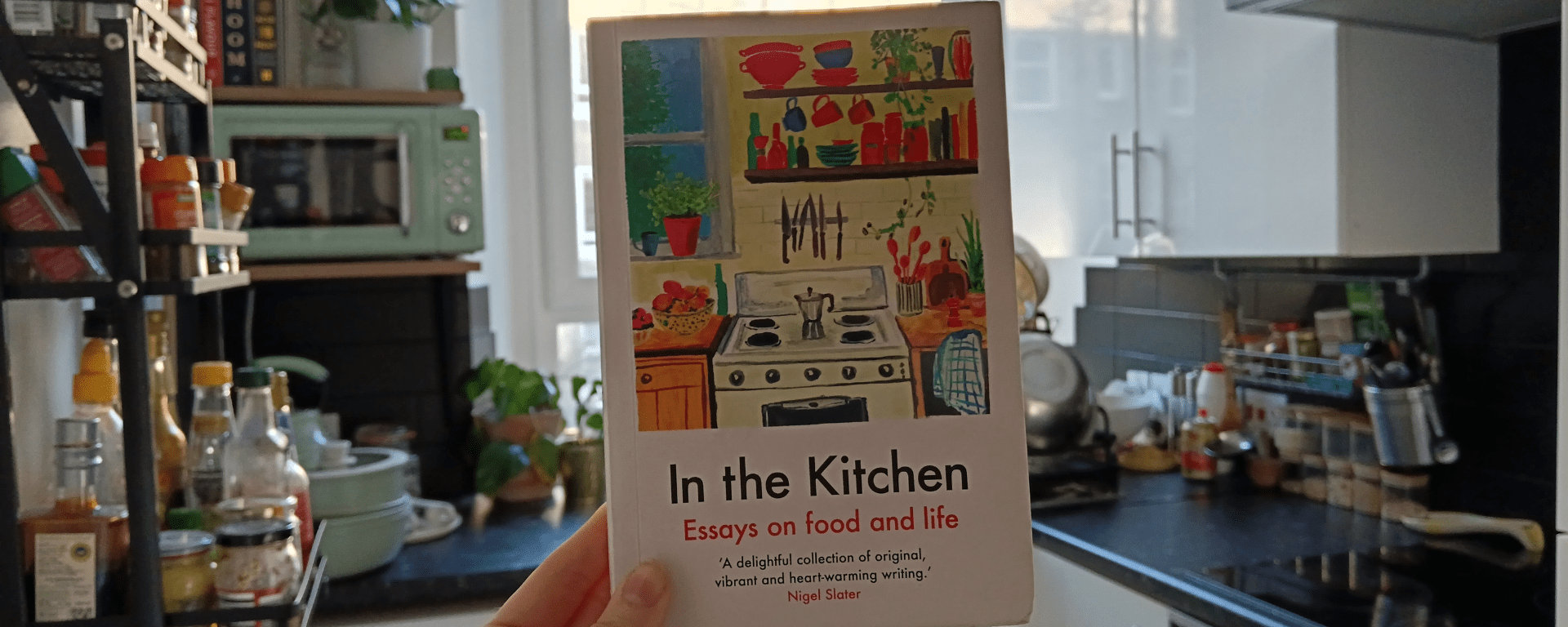 I hold up a book called 'In The Kitchen' in my kitchen