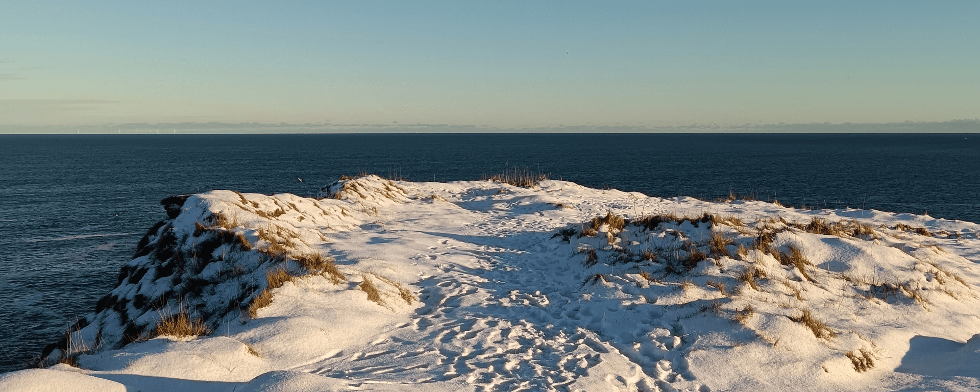 A snowy cliff edge overlooking the sea