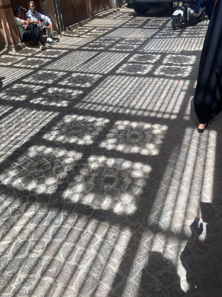 Patterned shadows coming through the street covers