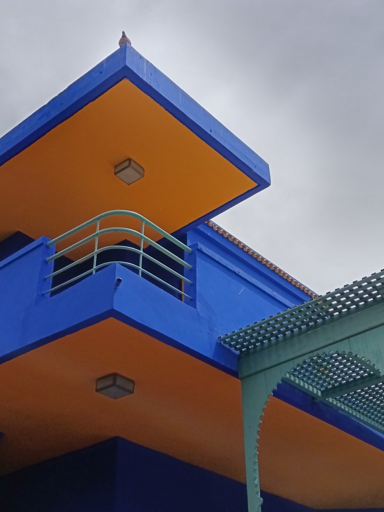 The bright blue and yellow museum building against the pale sky