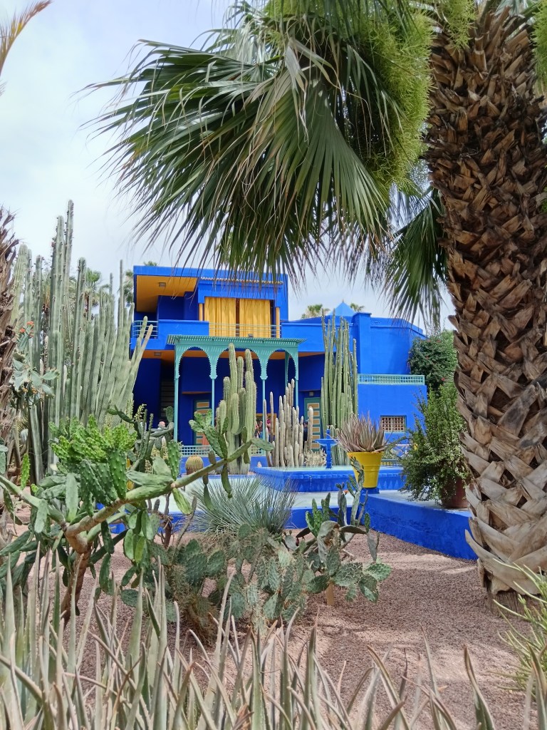 A bright blue building in the middle of a botanic garden