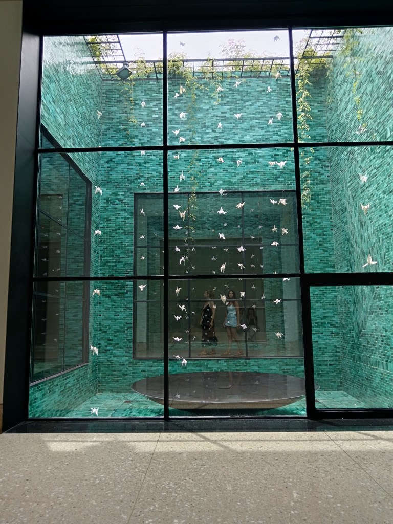 Strings of origami birds hang down in front of green tiles