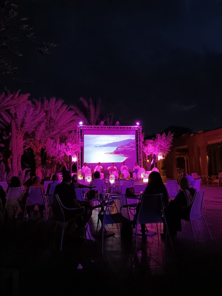 Pink light glows around a stage with traditional musicians
