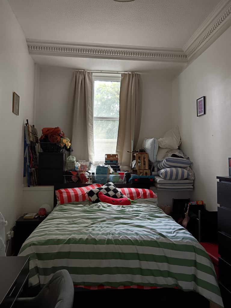 Two mattresses layered on top of each other, with stacks of my belongings piled up behind