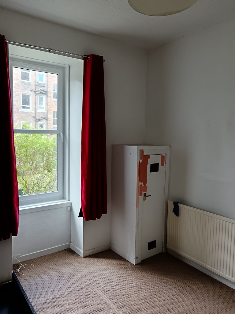 A large white room with red curtains that stop 2ft from the ground