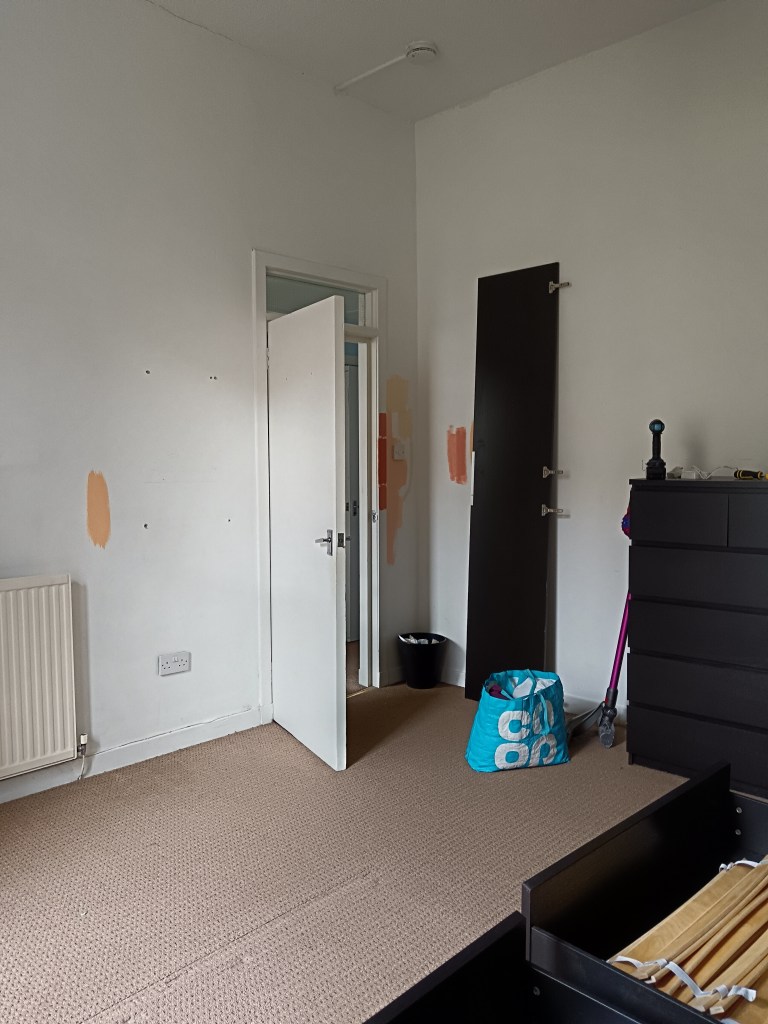 A plain white room with peachy orange paint samples randomly dotted about